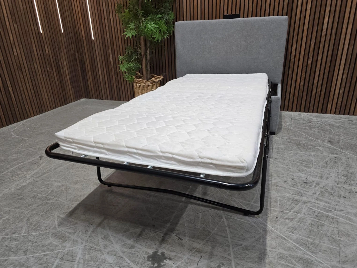 footstool with bed frame folded out to make a single bed